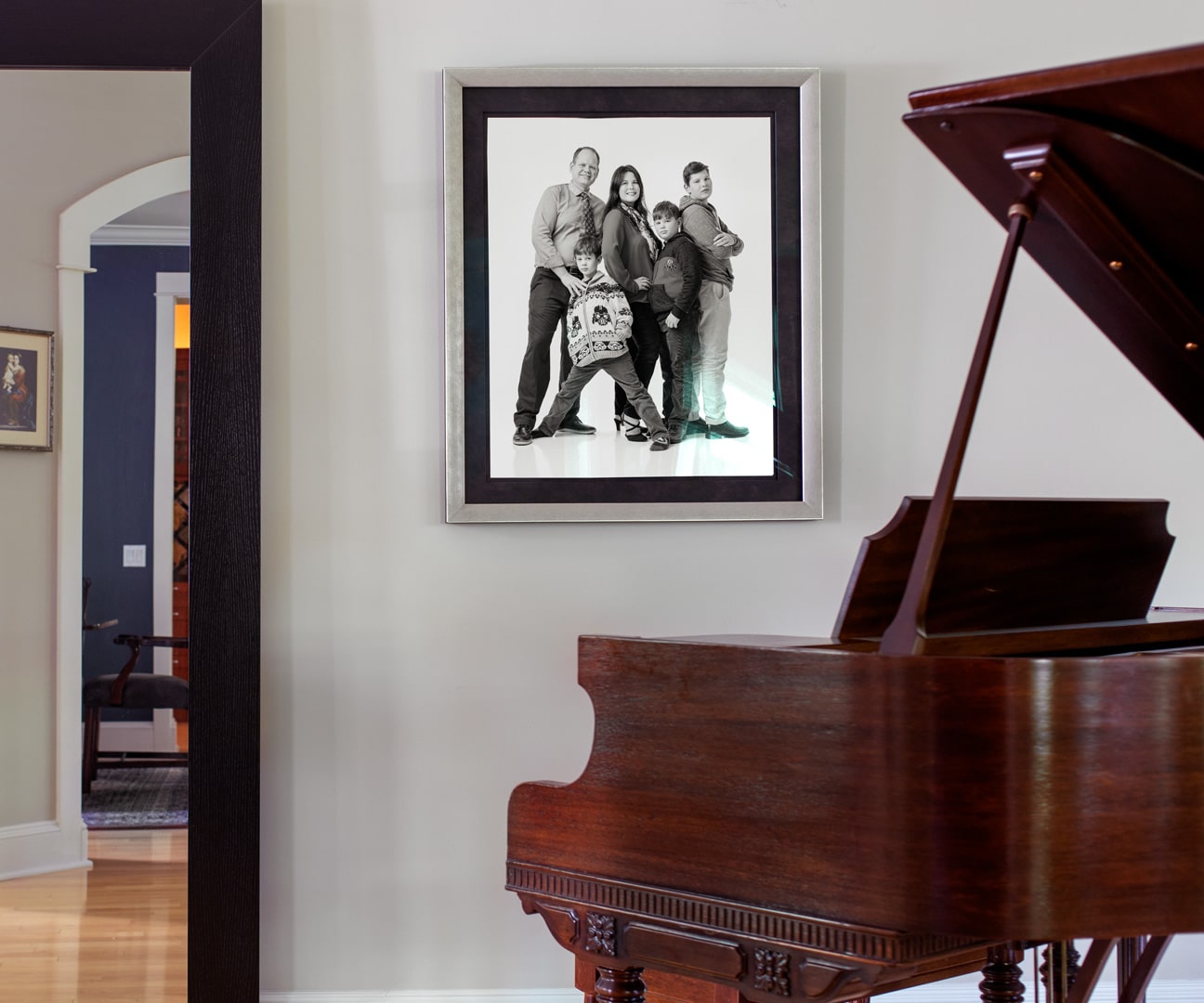 Family portrait hanging on the wall near a baby grand piano