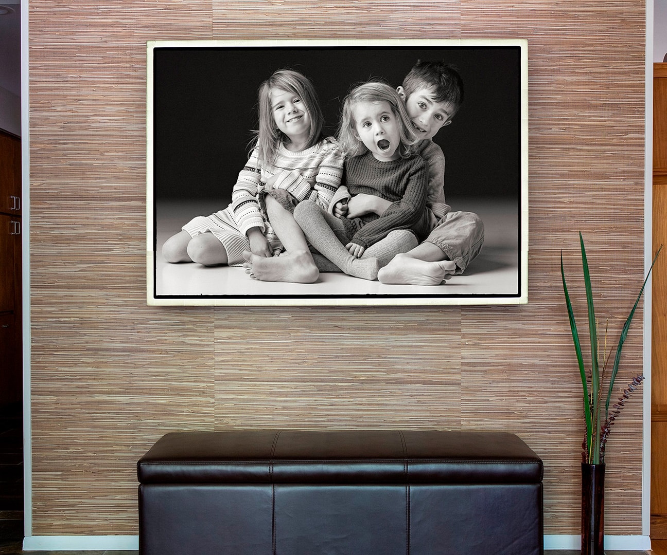 Stunning black and white portrait of three kids framed and hung in a designer foyer
