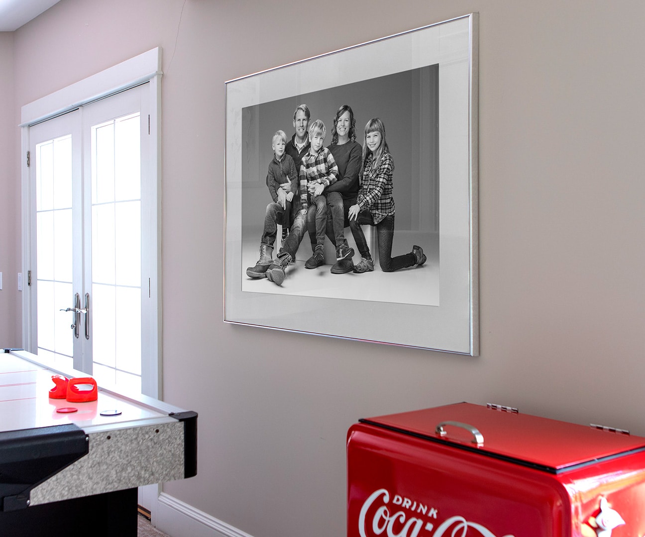 Black and white family portrait framed in silver, hung in an elegant game room