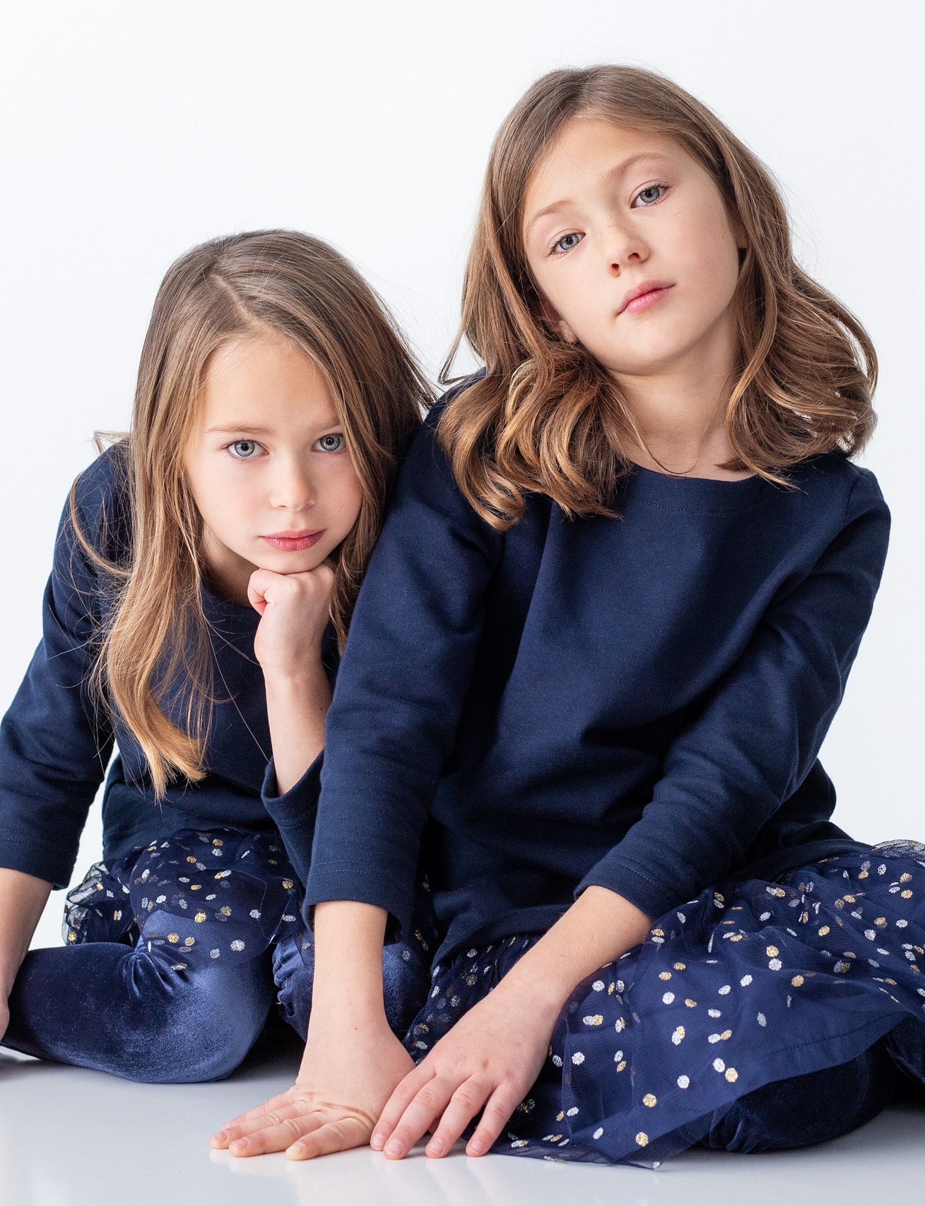 Kids portrait of two beautiful young sisters in matching blue dresses