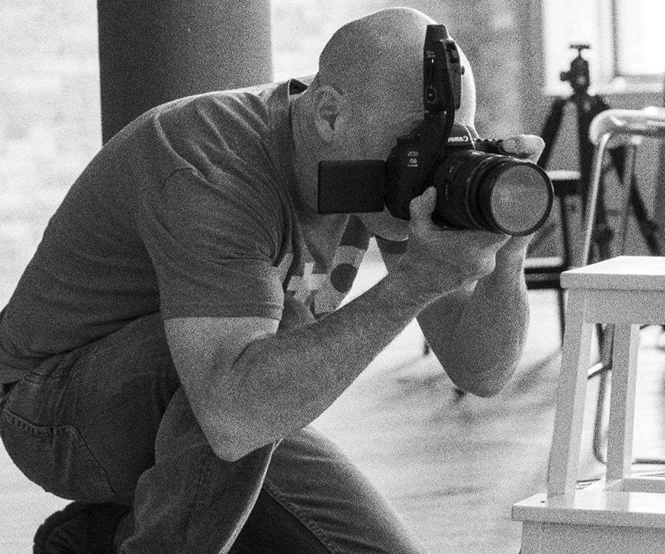 black and white behind the scenes shot of a photographer looking through his camera