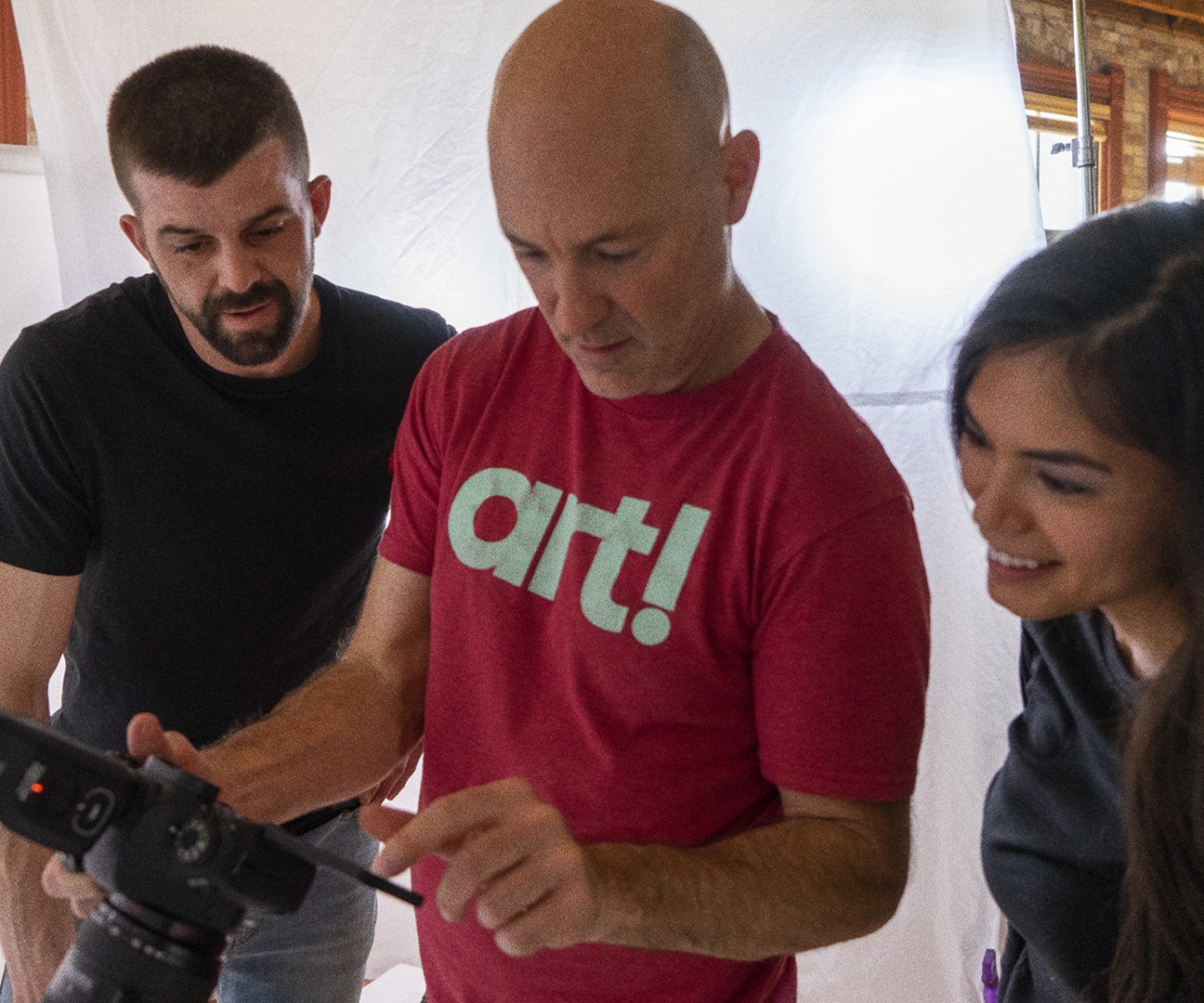 behind the scenes photo of a photographer and a family looking at their photos on the back of his camera
